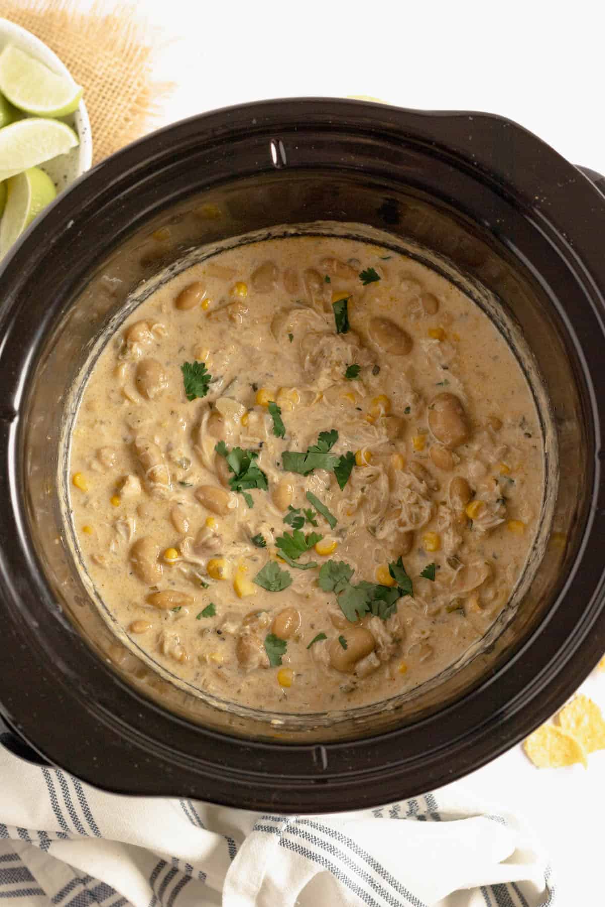 A black crockpot filled with white chicken chili.
