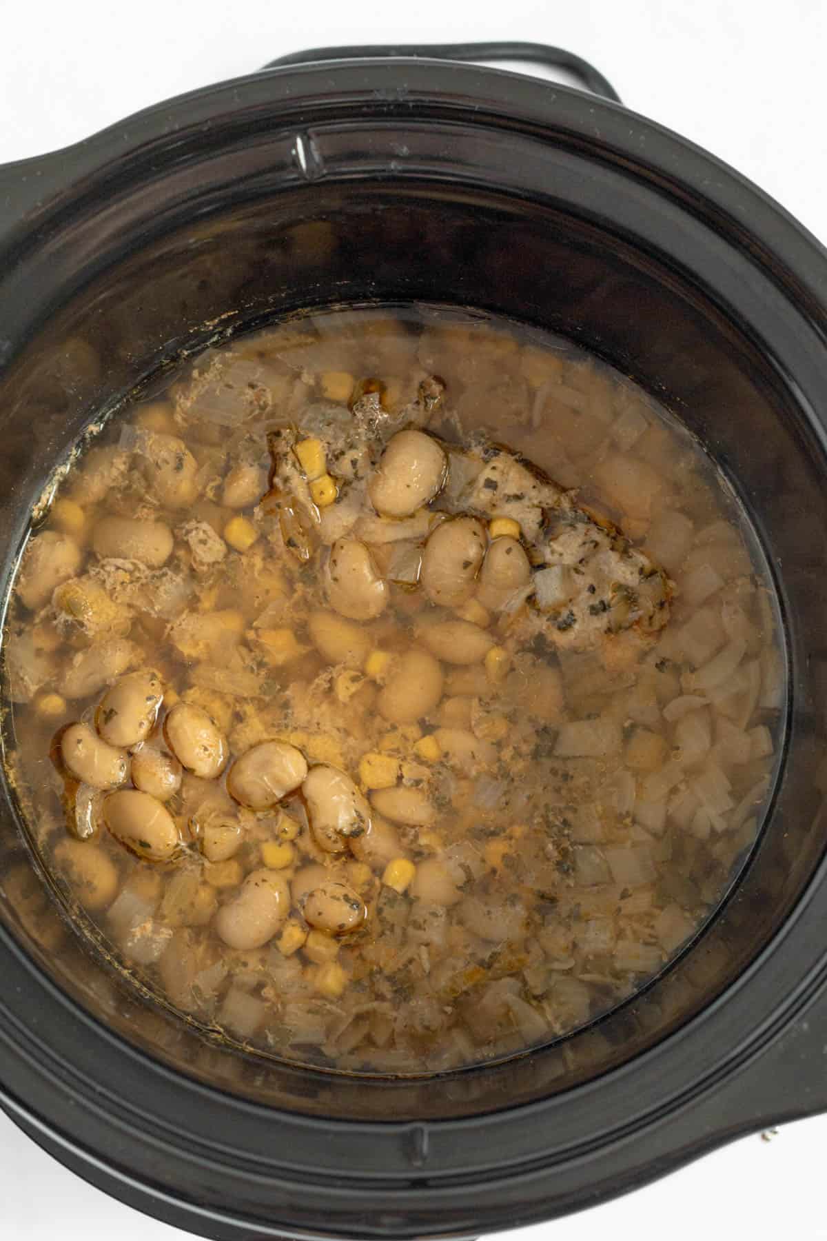 Stirring white chicken chili ingredients together in a slow cooker.