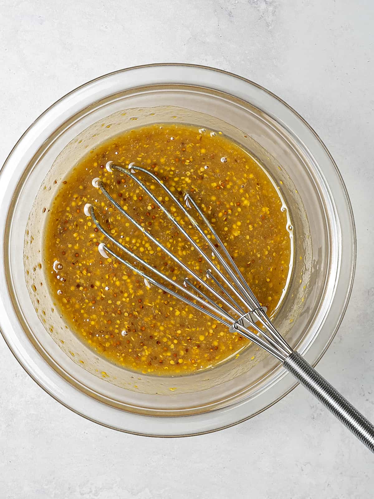 Whisking honey mustard sauce in glass bowl