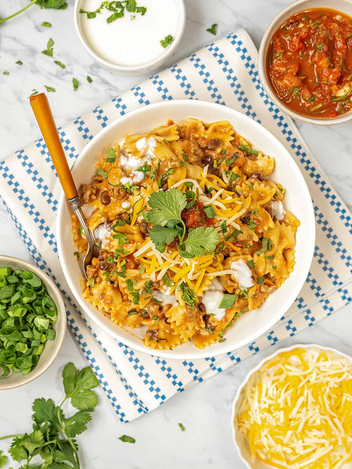 Overhead view of Instant Pot taco pasta with bowls of garnishes