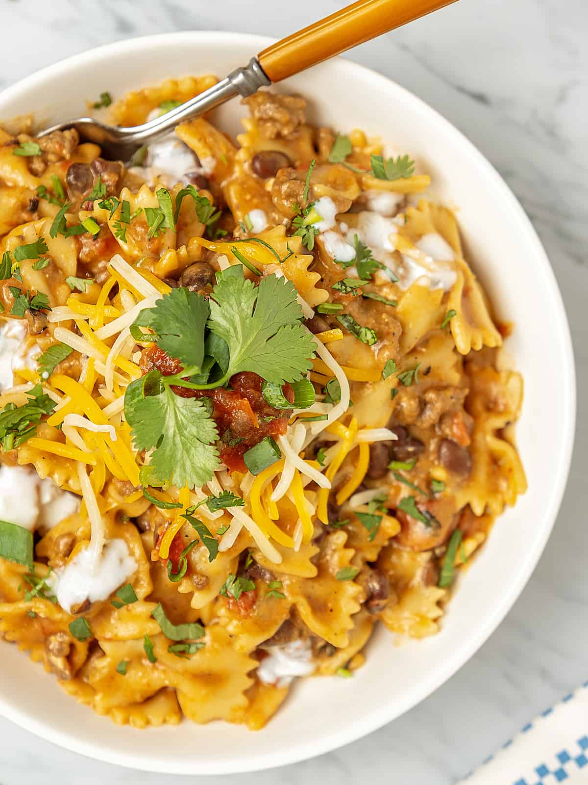 Instant Pot taco pasta in bowl with fork and cilantro sprig
