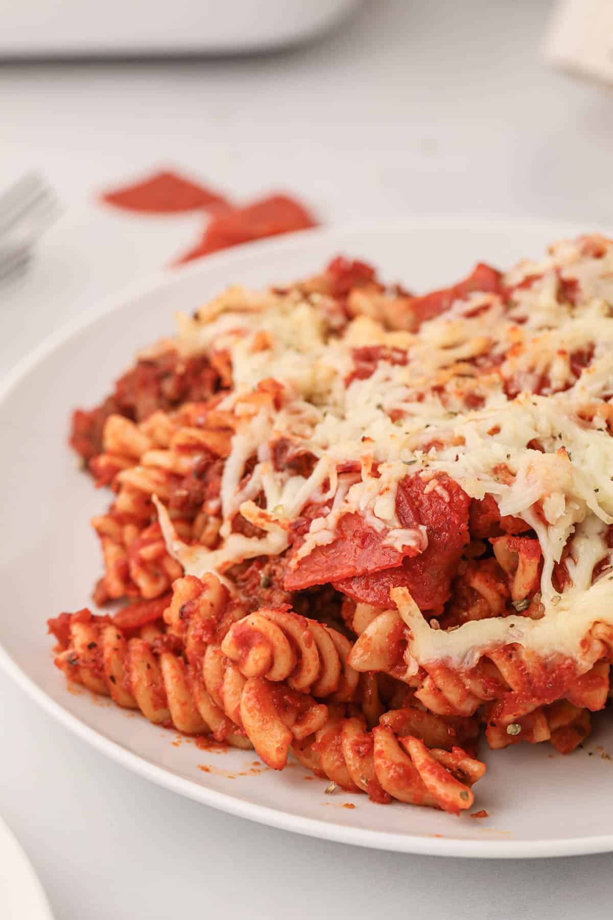 A close image of rotini pasta in marinara sauce with Italian sausage, pepperoni, and mozzarella cheese.