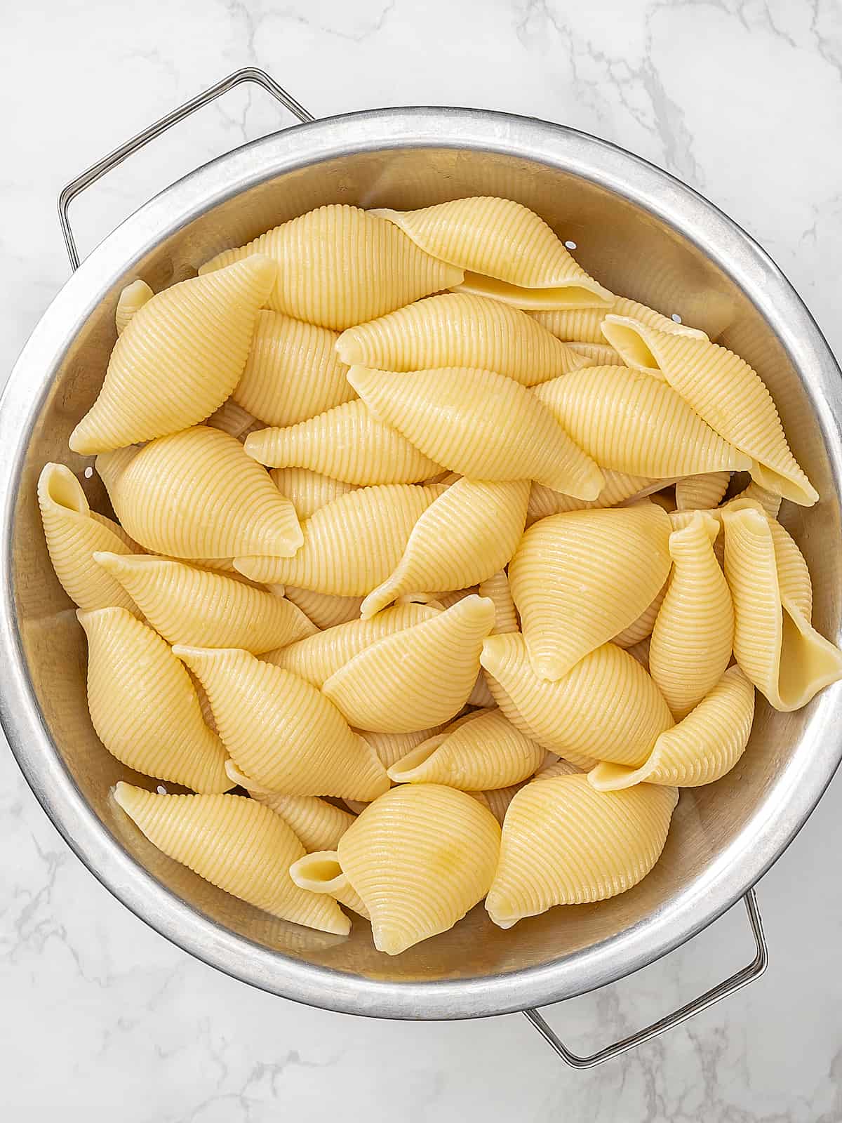Colander full of cooked jumbo pasta shells