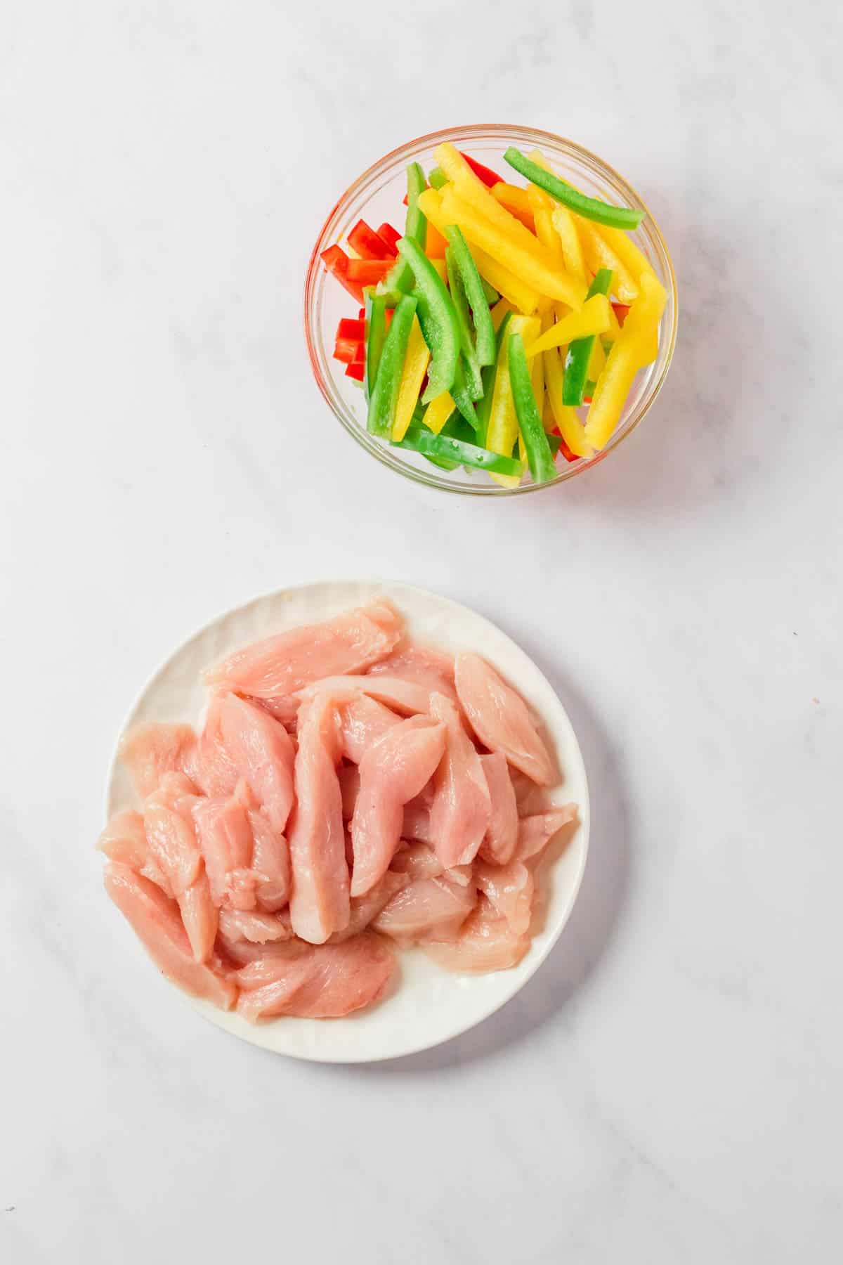 Sliced chicken breast and red, yellow, and green bell peppers.