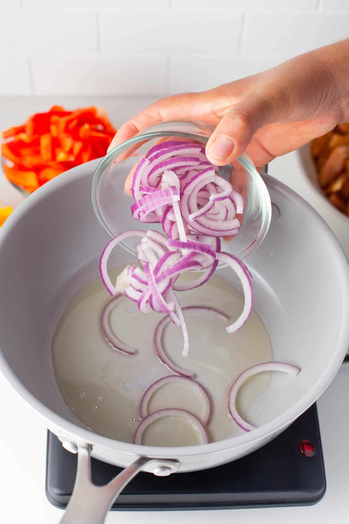 Adding sliced onions to hot oil in a large pan.