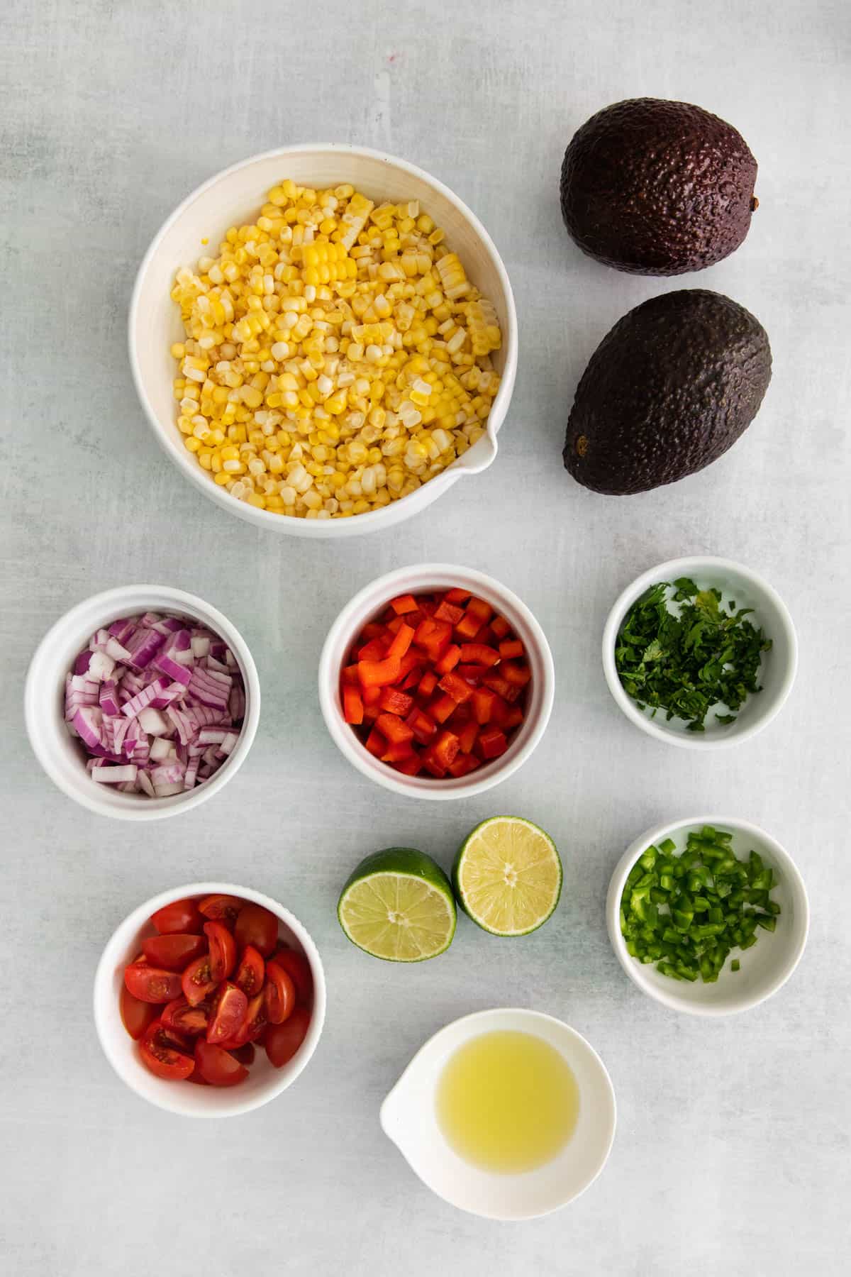 Ingredients for corn and avocado salad in separate bowls.