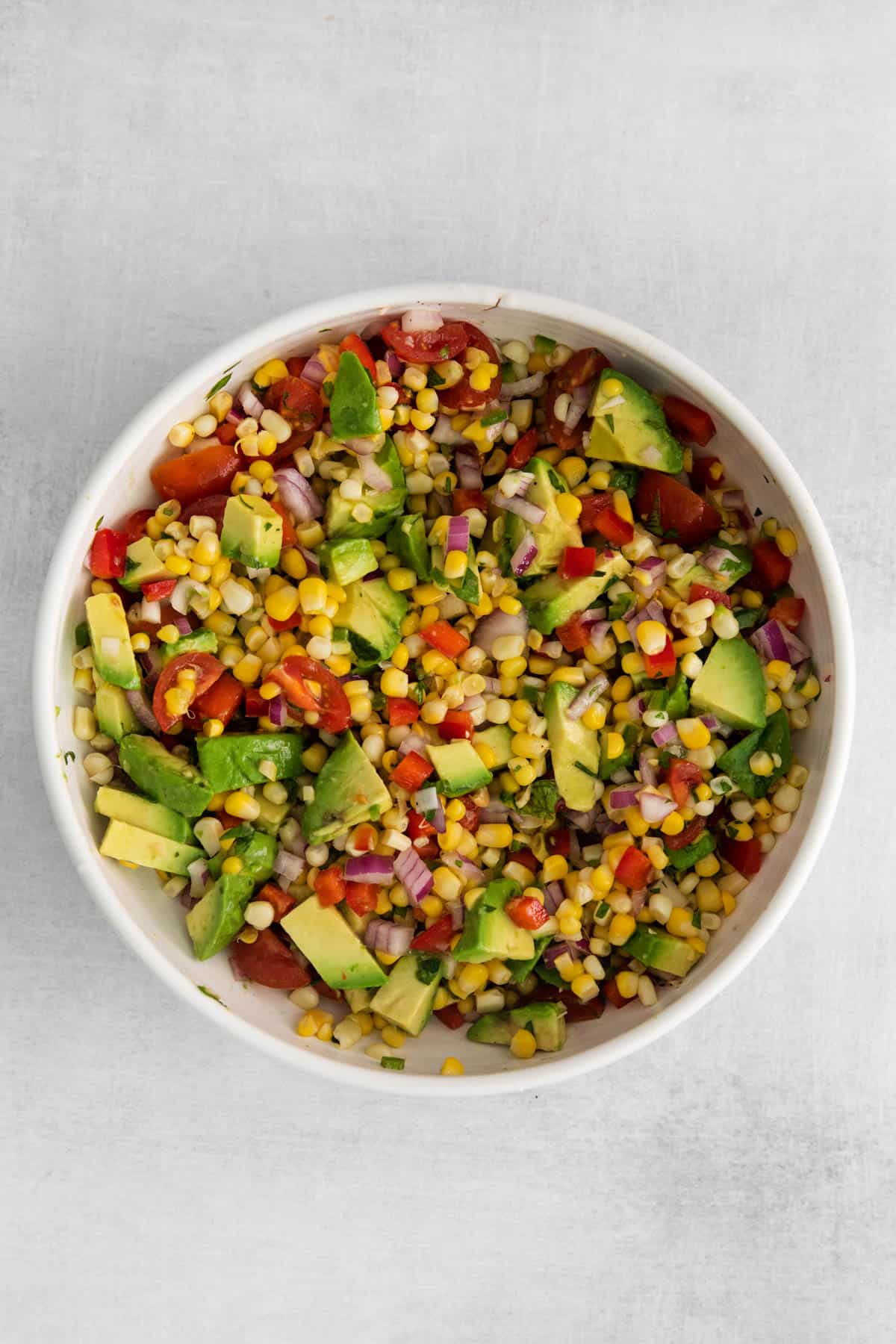A large serving bowl of corn and avocado salad.