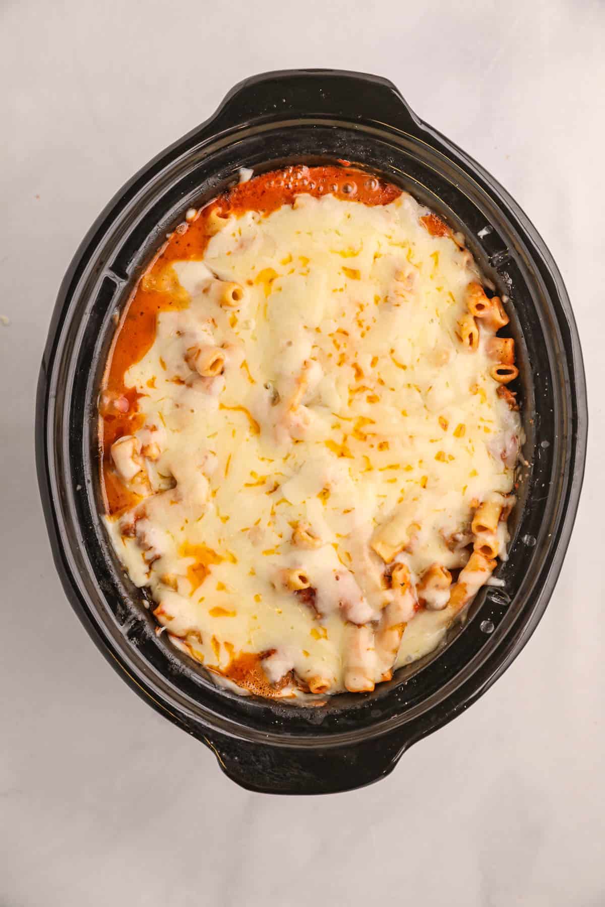 Melted mozzarella cheese on top of baked ziti in the slow ccooker.