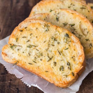 Slices of homemade easy garlic bread on a wooden surface.