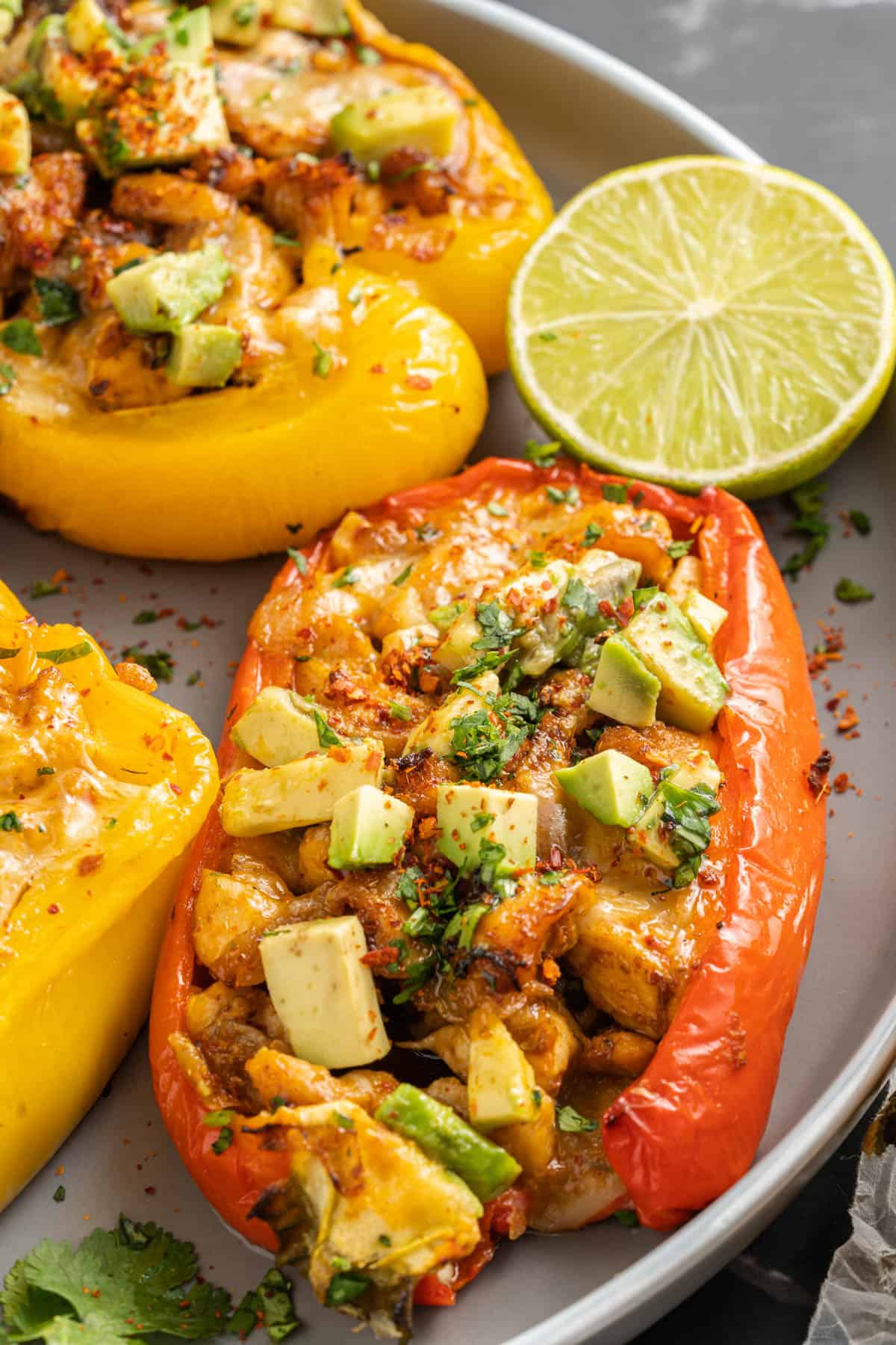 Fajita chicken stuffed bell peppers on a plate next to half a lime.
