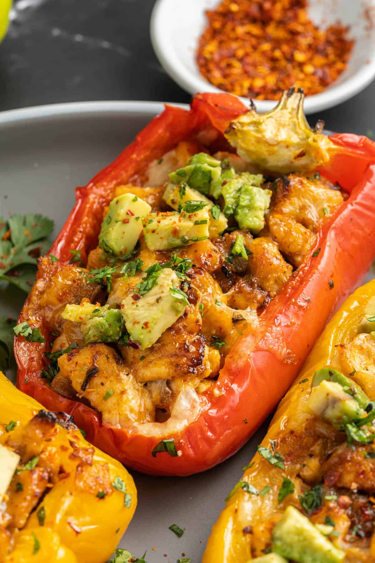 A red bell pepper filled with fajita chicken and topped with cheese and diced avocado.