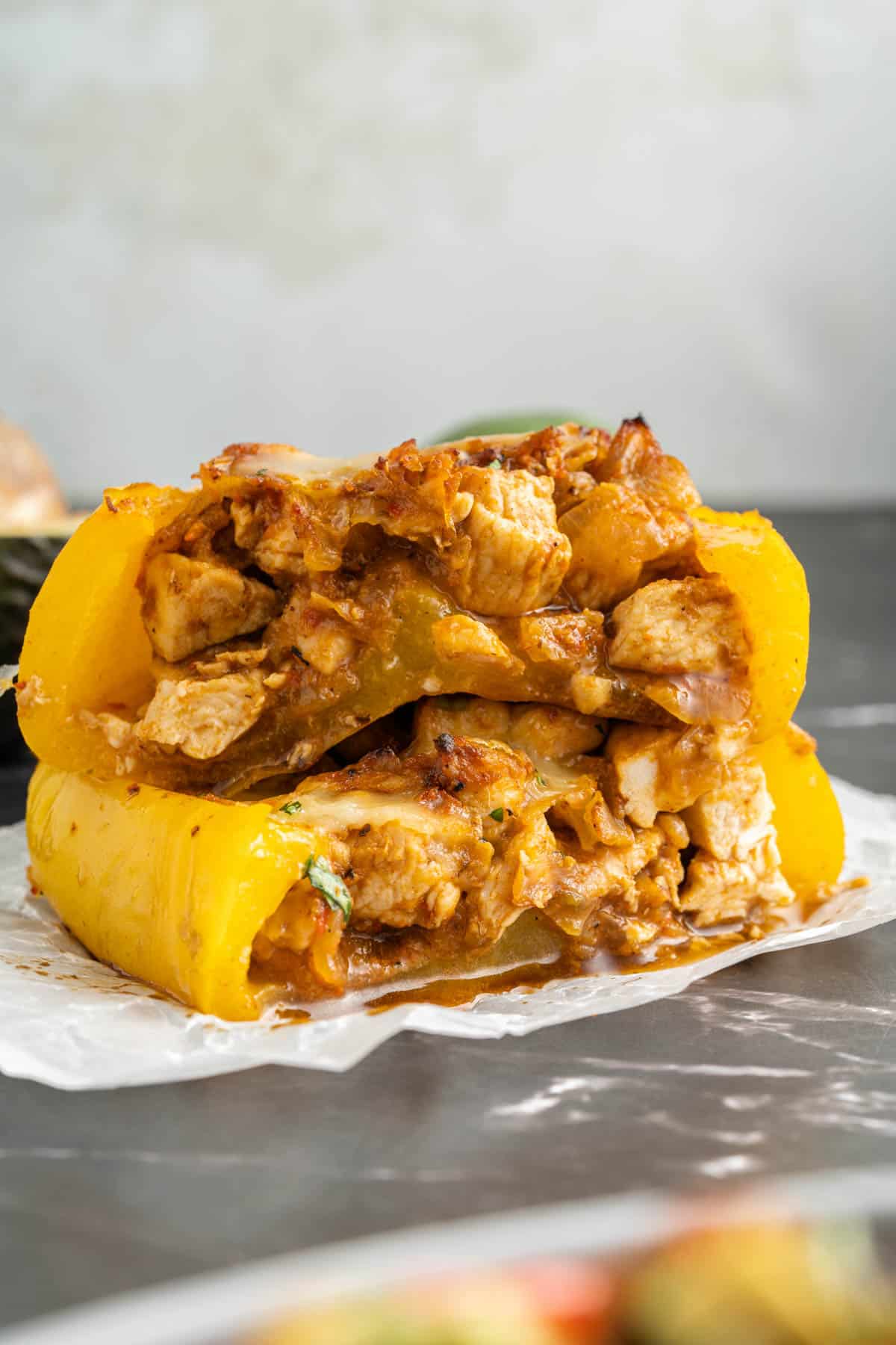 Stacked fajita chicken stuffed peppers that have been cut in half.
