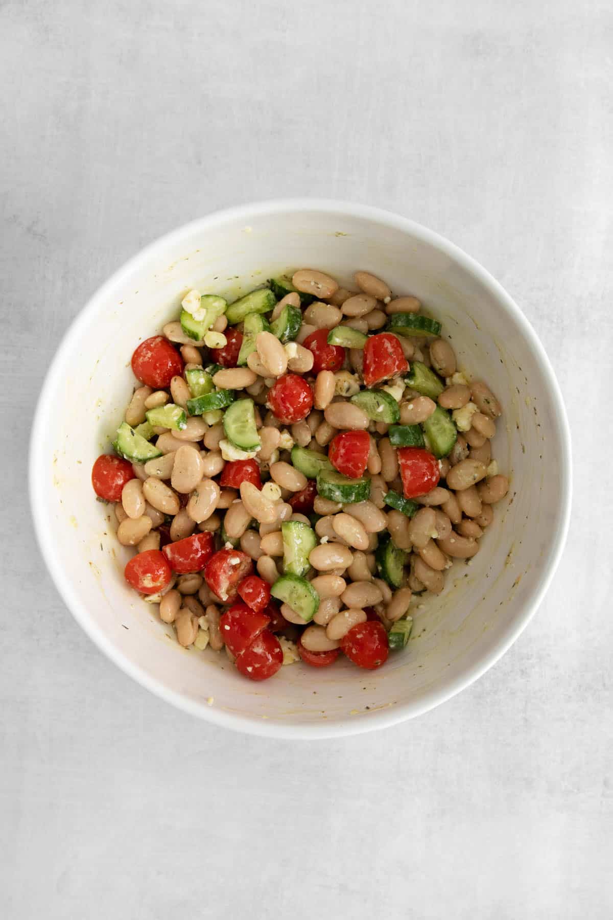 Mixed Mediterranean white bean salad ingredients in a bowl.