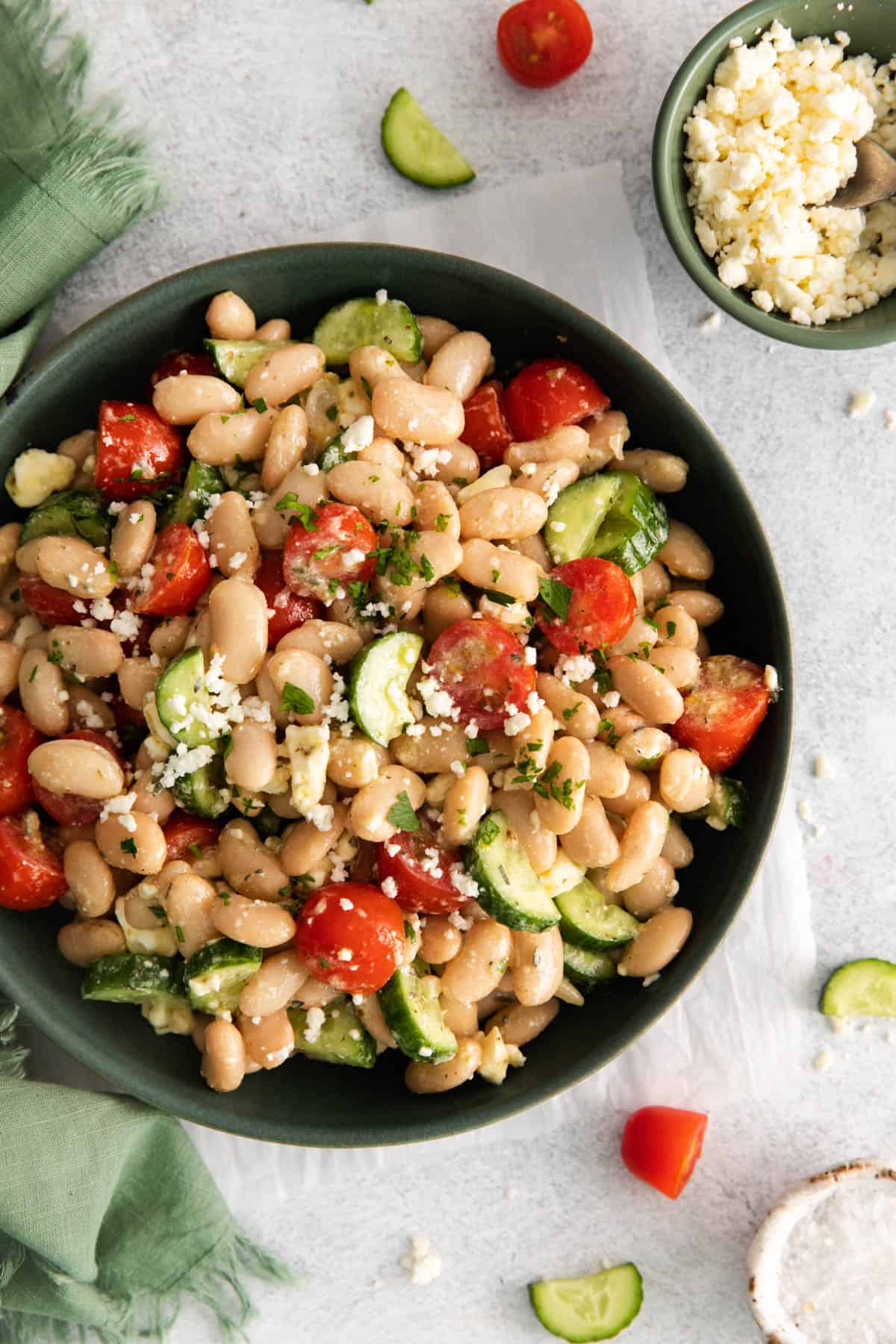 A plate of Mediterranean salad with white beans, cucumbers, tomatoes, and feta cheese.