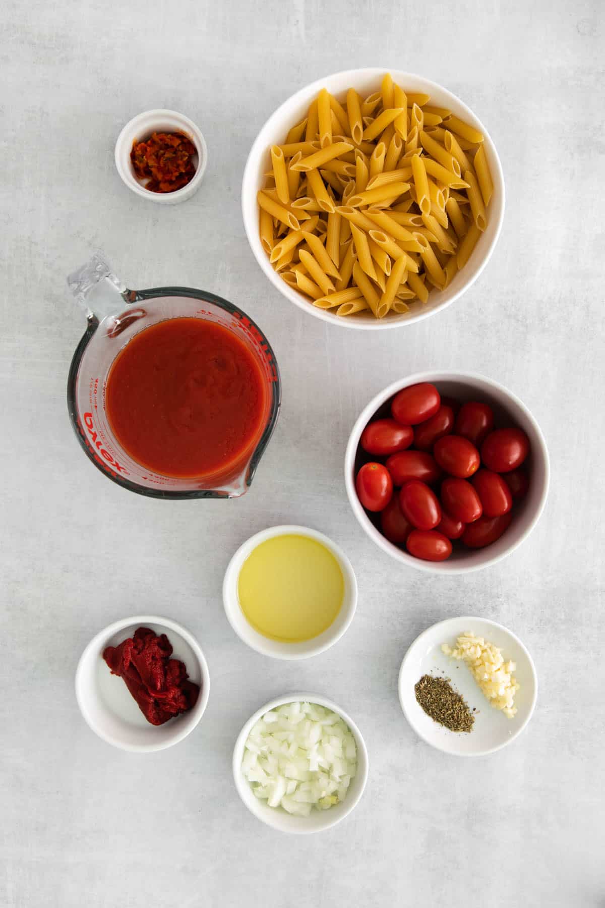 Ingredients for making penne all'arrabbiata in separate bowls.