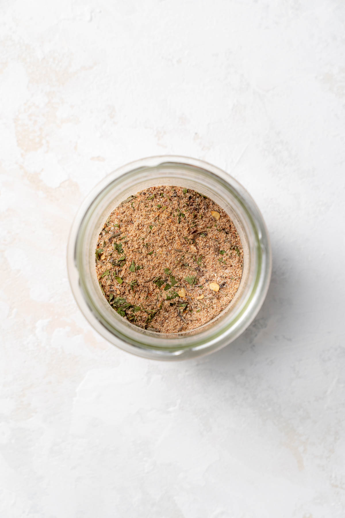 Overhead view of a glass jar containing blended spices.