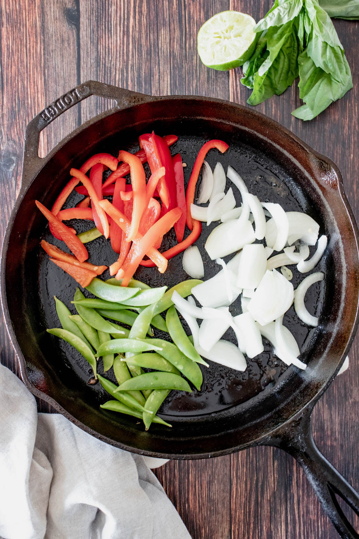 Sliced onion, red bell peppers and snow peas in a skillet before cooking. 