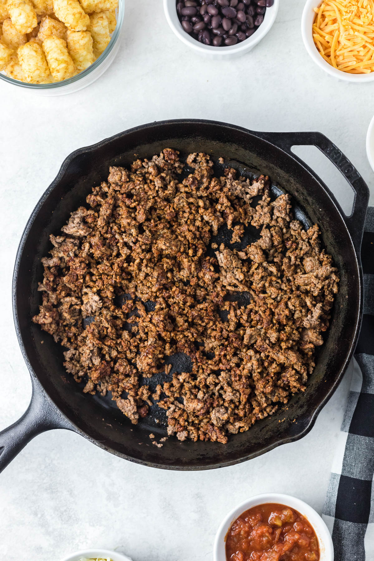 Ground beef is displayed already browned in a black skillet.
