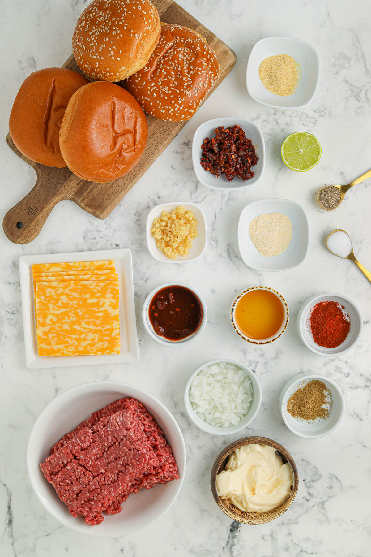 Overhead image of small bowls and plates containing ingredients for chipotle burgers.