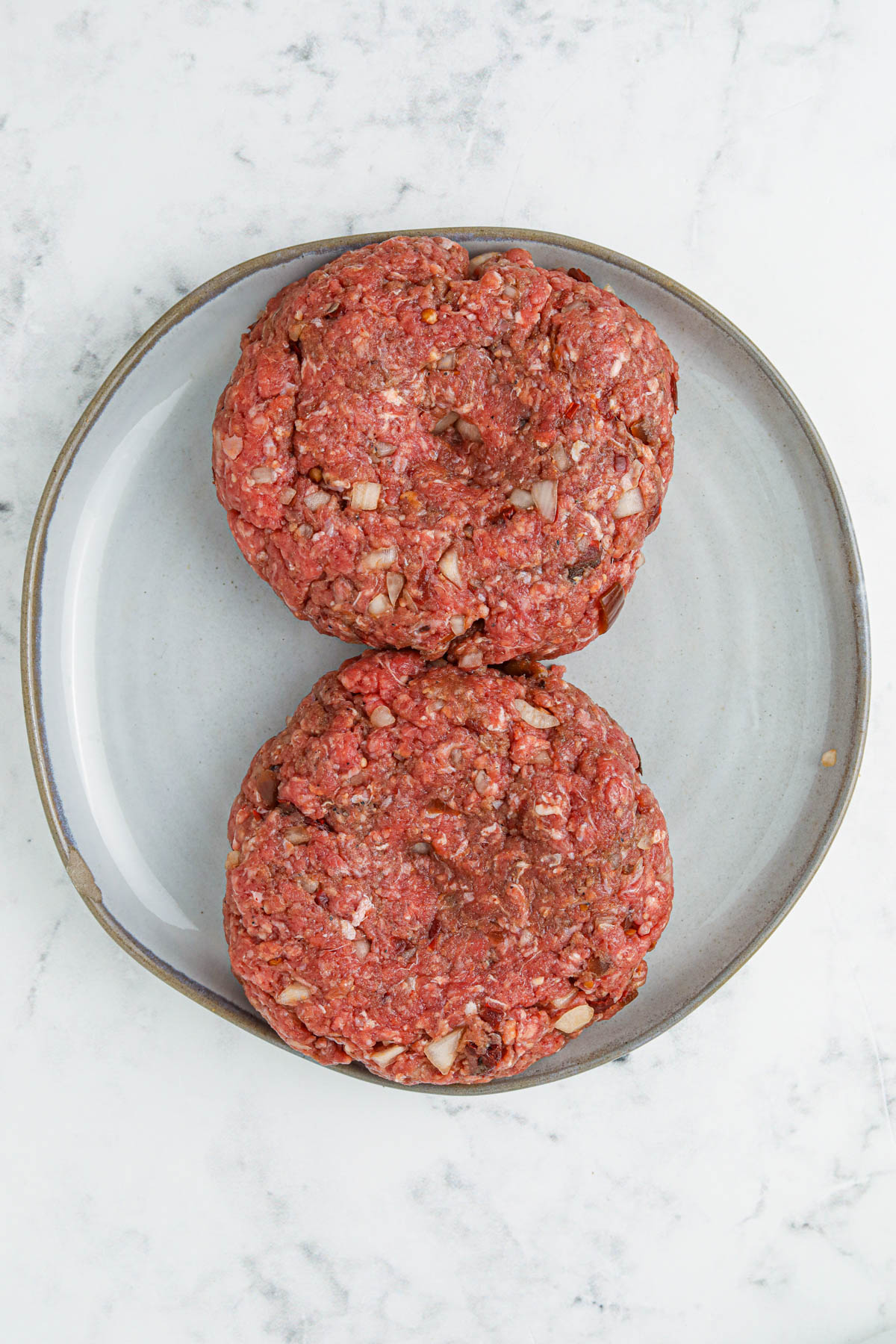 Overhead image of two formed hamburger patties, before they are cooked.