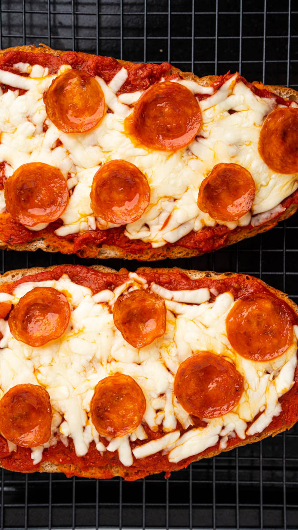 Close up image of two slices of cooked french bread pepperoni pizzas. 
