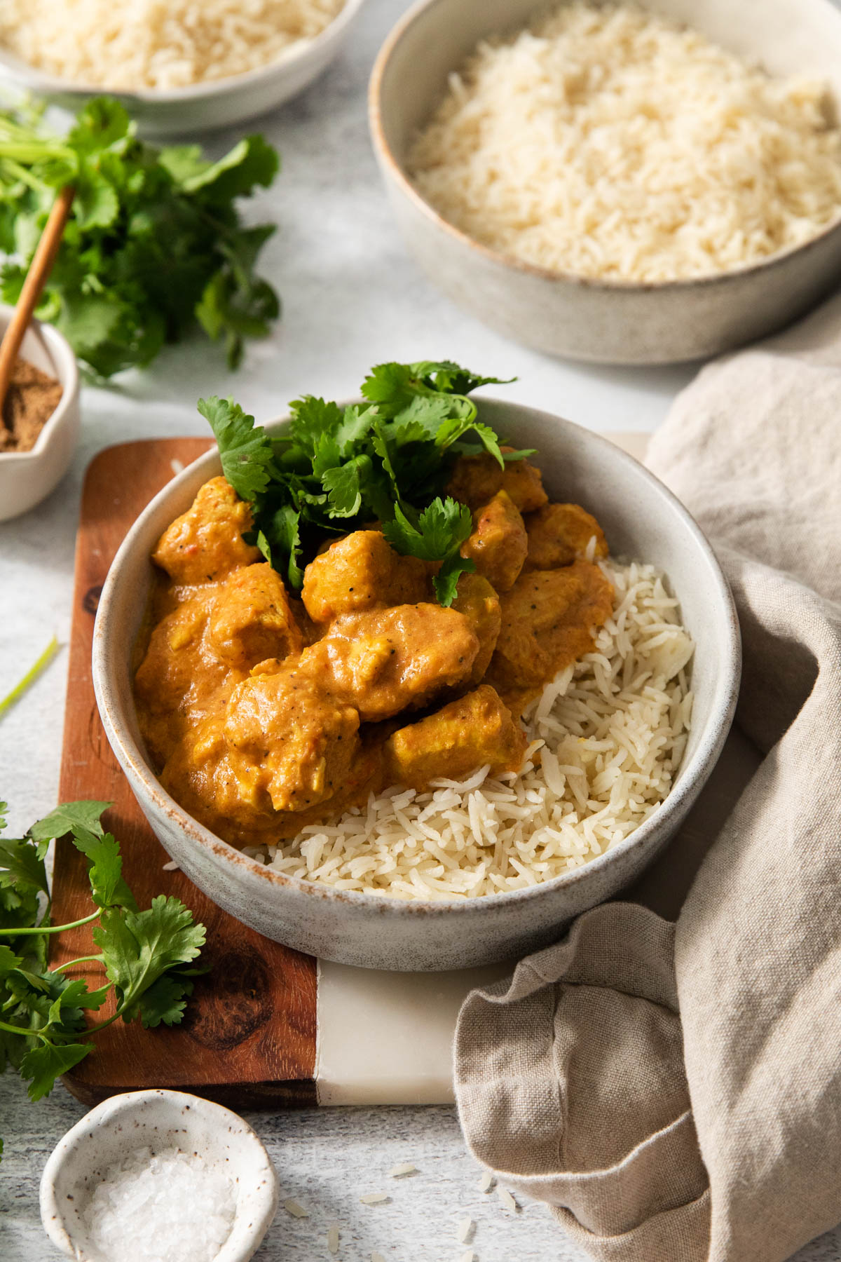 An image of slow cooker butter chicken in a bowl with basmati rice and cilantro.
