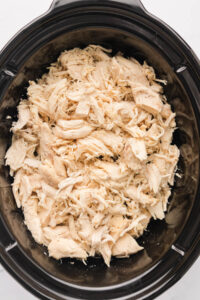 An overhead image of slow cooker shredded chicken in a crock pot.