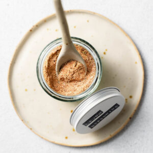 An overhead image of a jar of homemade cajun seasoning with a spoon in it.
