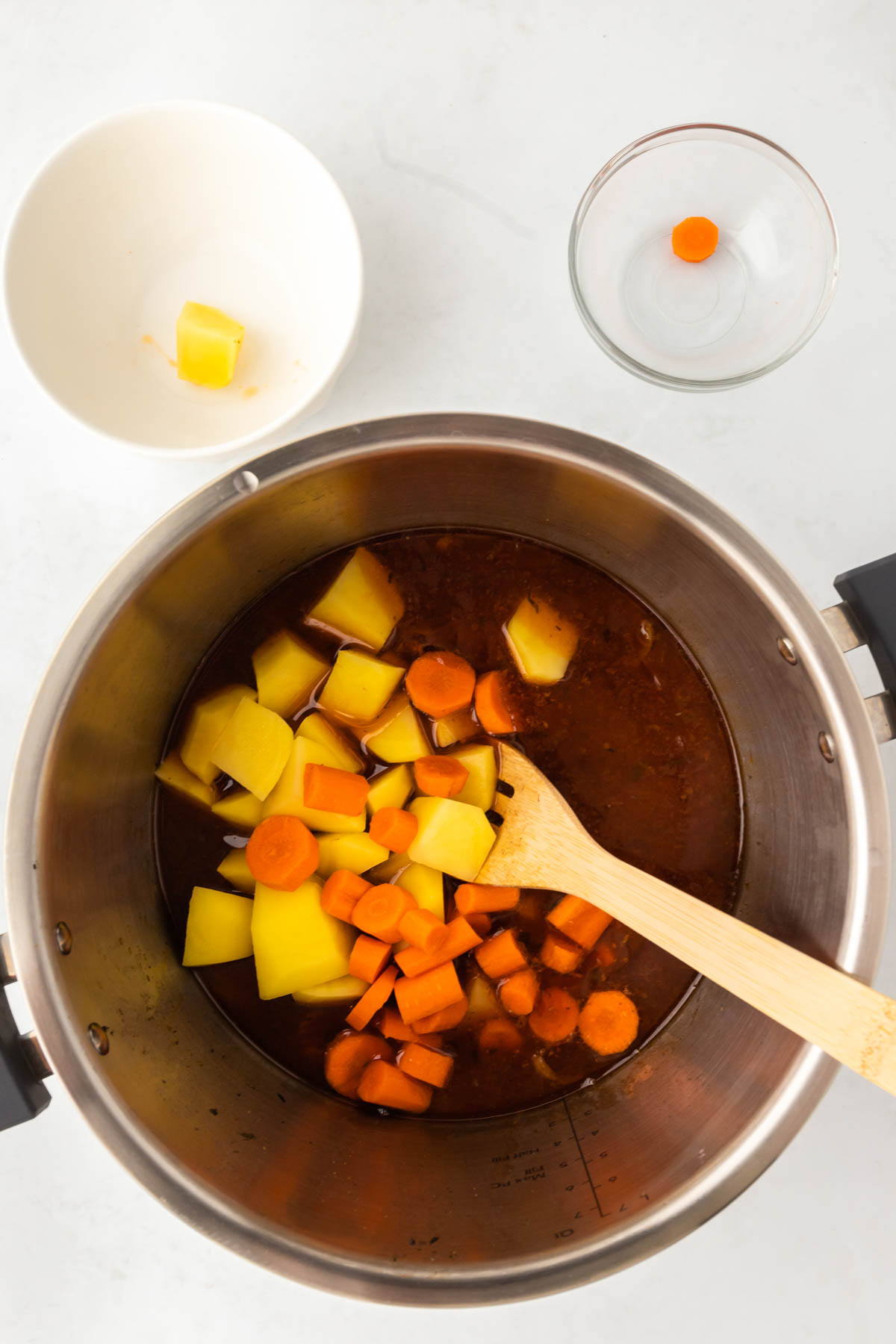 Chopped potatoes and carrots are added to broth in an Instant Pot.