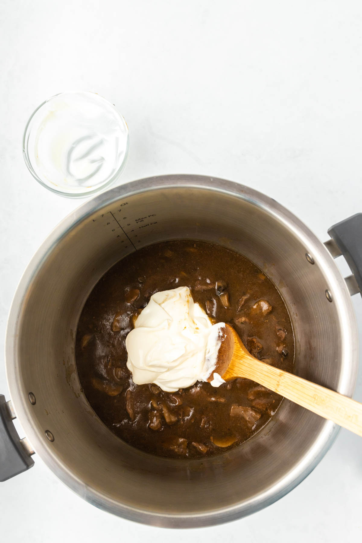 Sour cream is stirred into a beef mixture in an Instant Pot. 