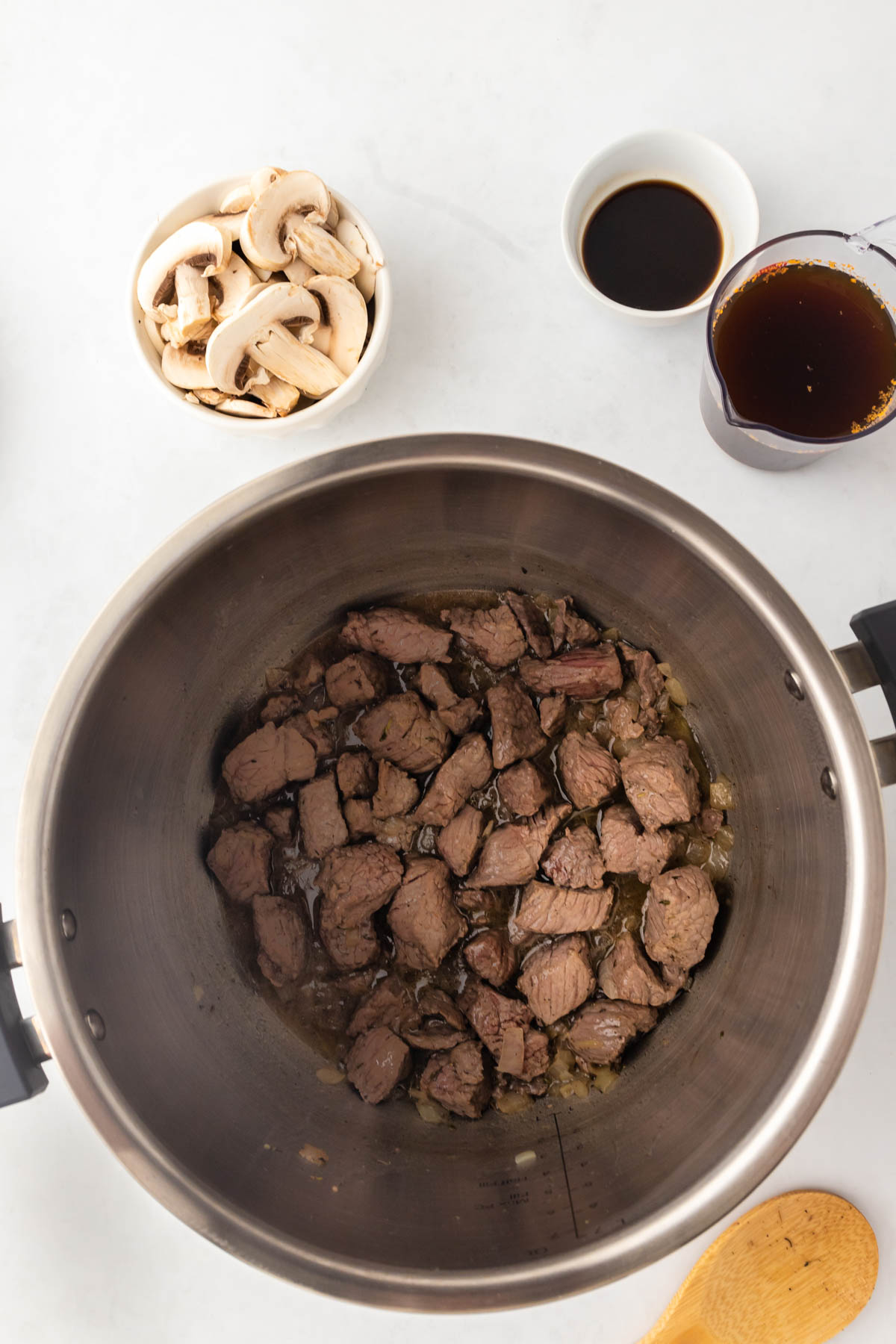 Browned beef is resting in the bottom of an Instant Pot insert. 