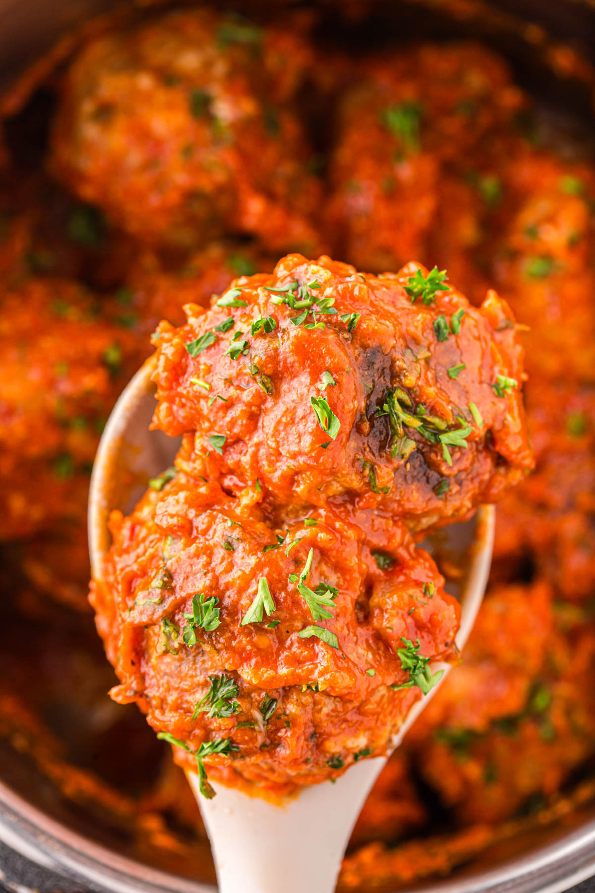 A close image of meatballs in sauce on a serving spoon.