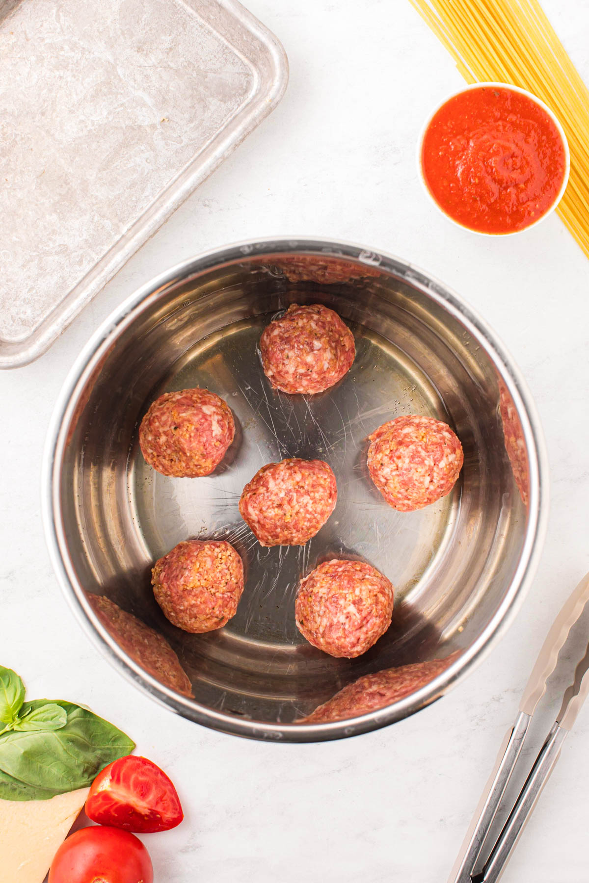 Adding meatballs to the bottom of an instant pot to sear.