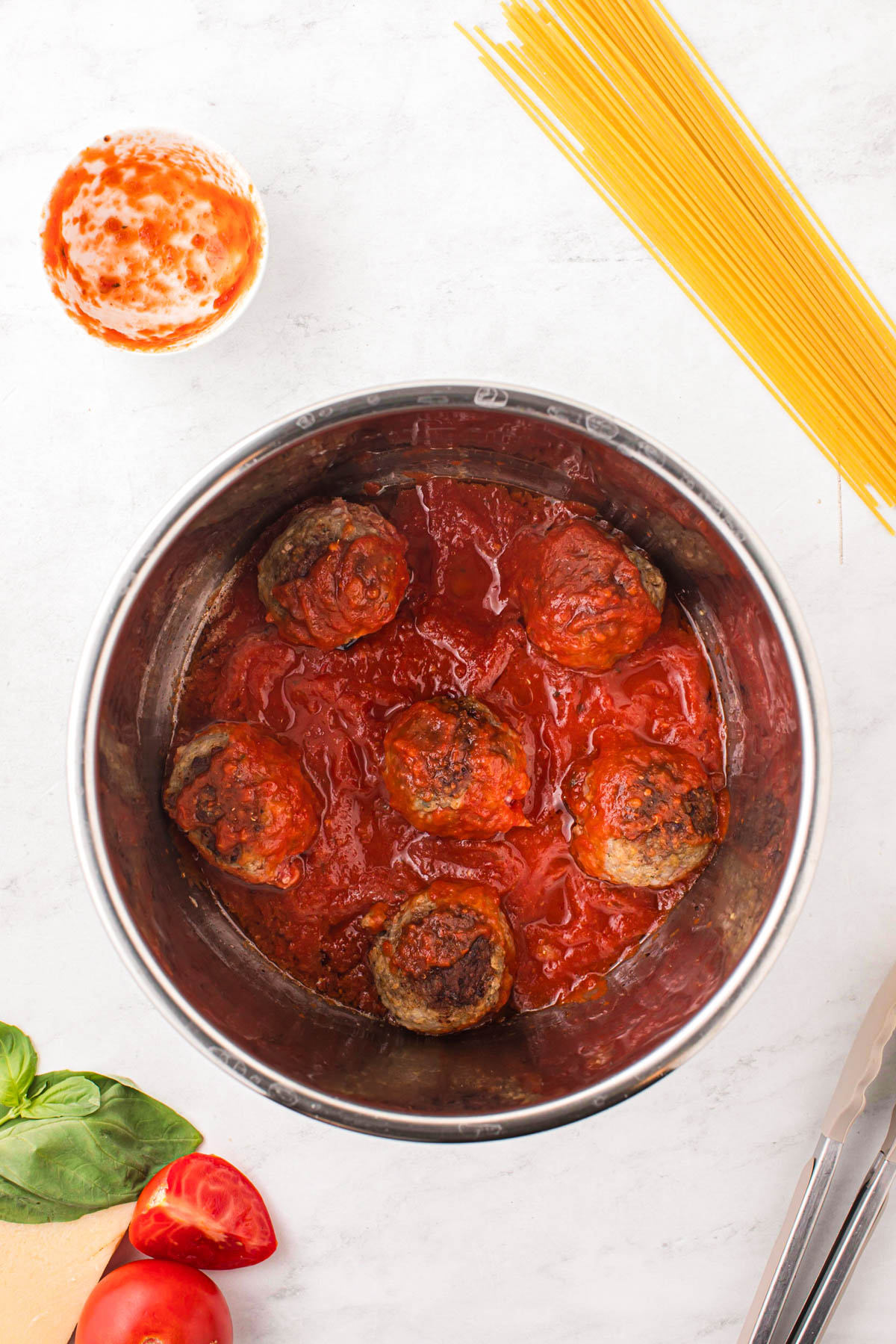 Adding sauce to seared meatballs in the instant pot.