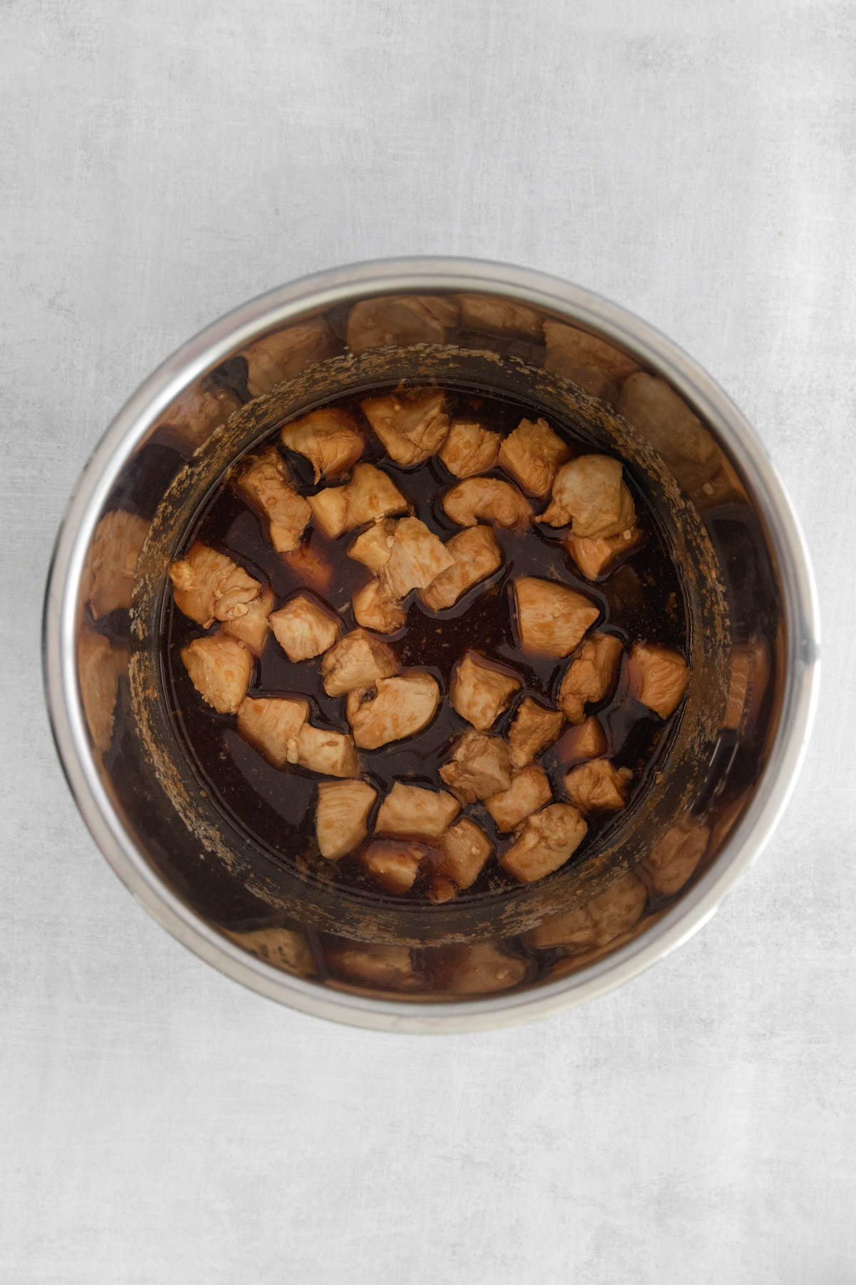 Cooked chicken in a teriyaki sauce is resting in an Instant Pot insert. 