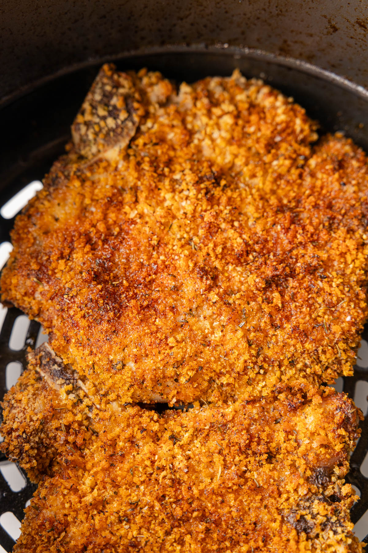 Overhead image of a cooked pork chop, with a golden brown crust. 