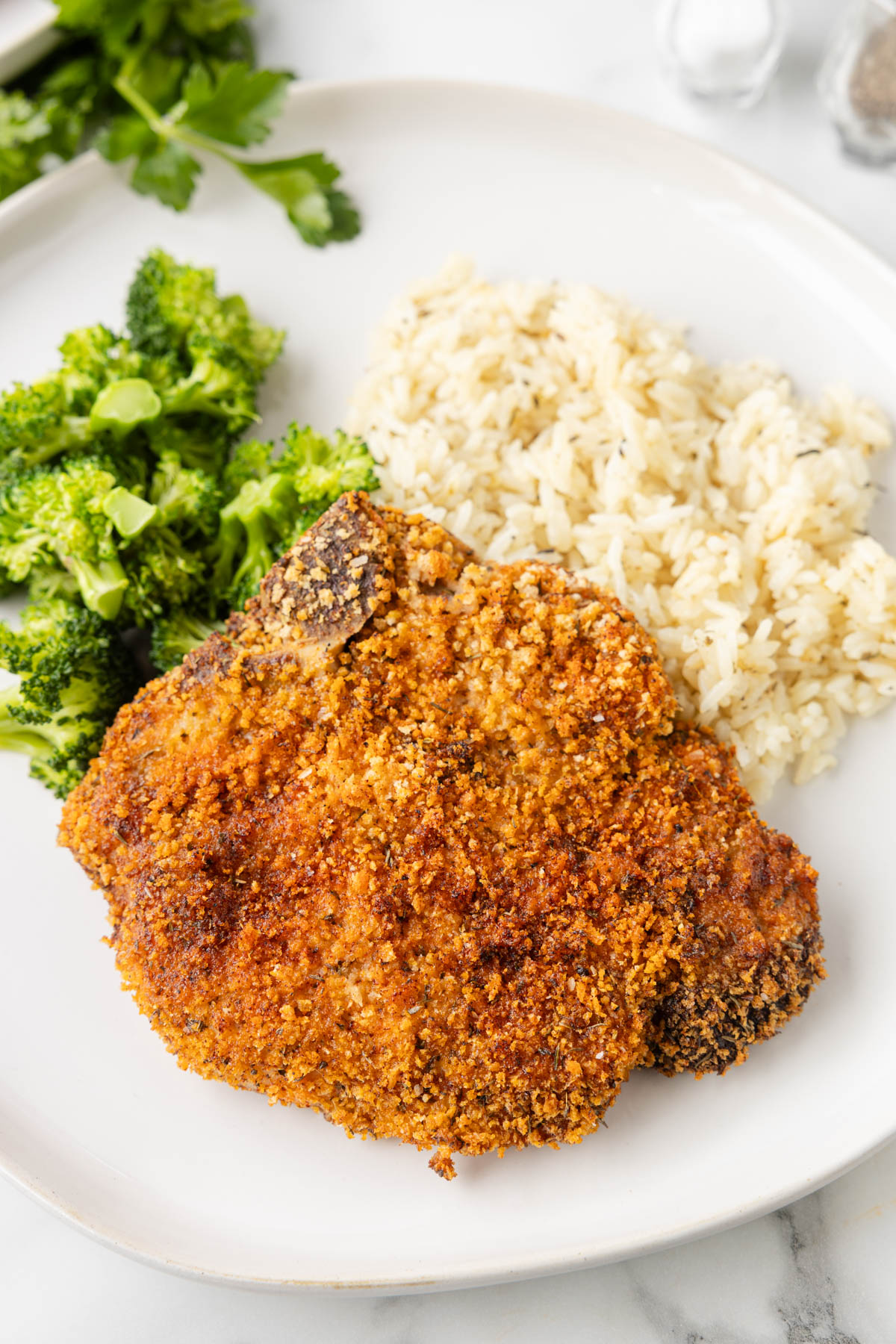 Pork chops are served with broccoli and rice. 