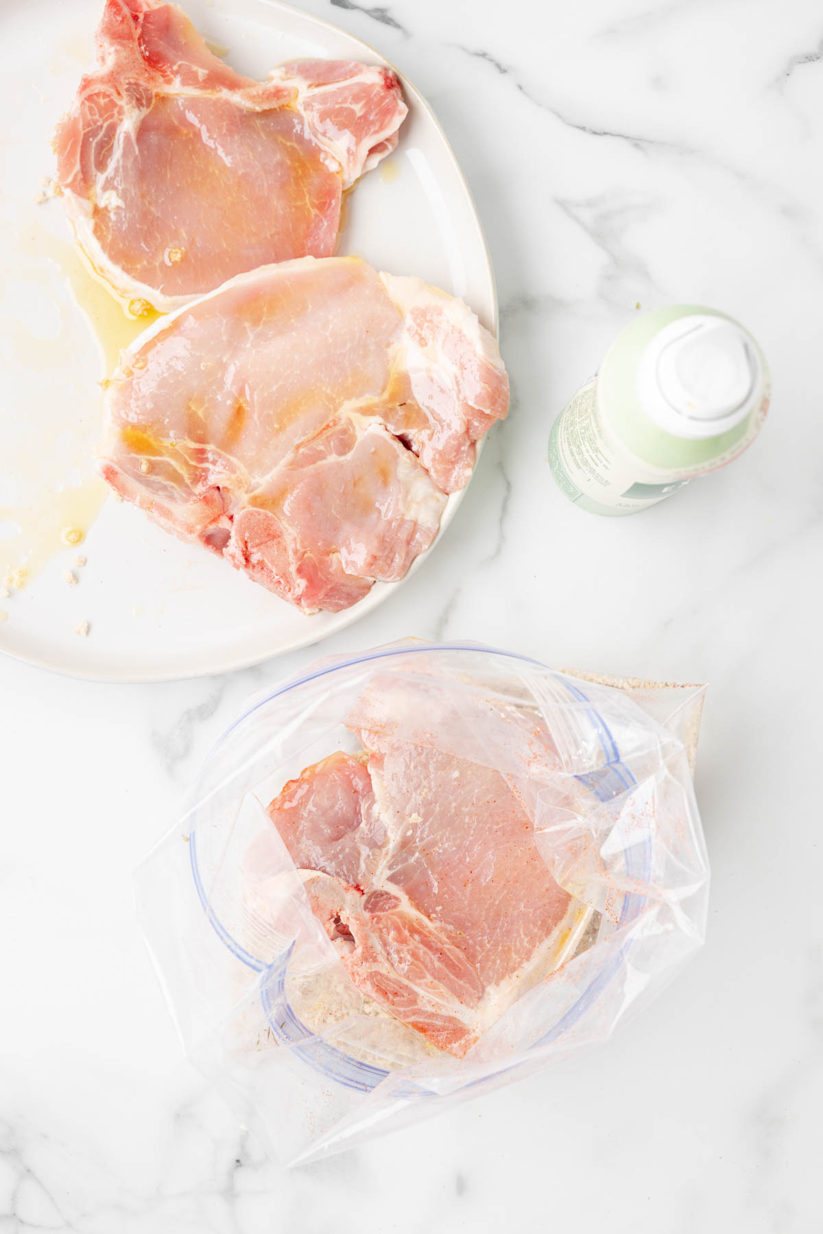 Uncooked pork chops are being pressed into a zip top bag containing a breadcrumb and spice mixture, prior to cooking in an air fryer. 