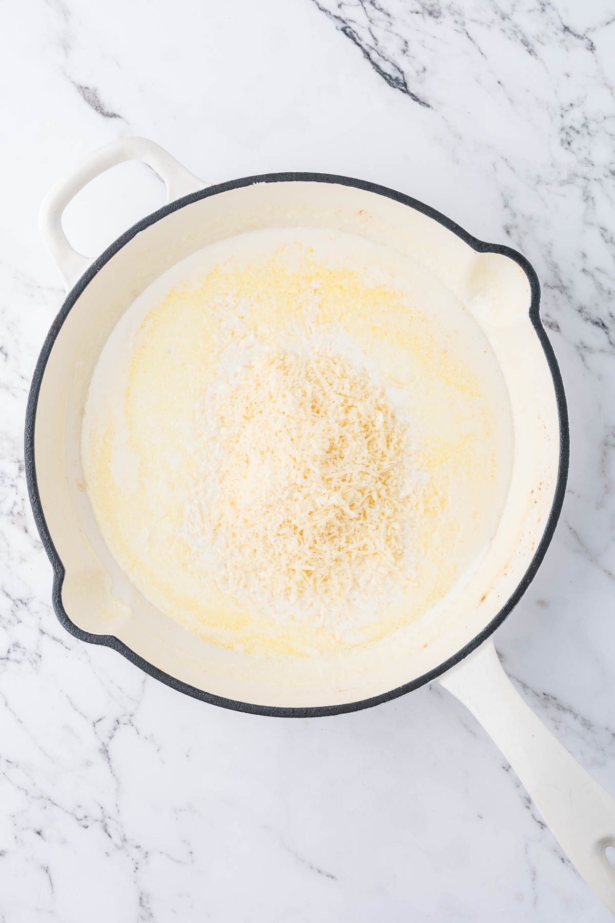 Cream, garlic and Parmesan cheese are simmering in a large pot. 