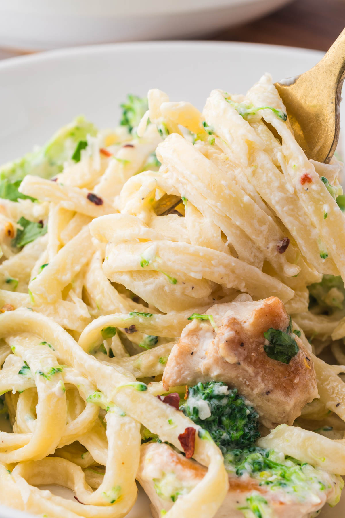 Fettuccini noodles are twirled around a gold fork.