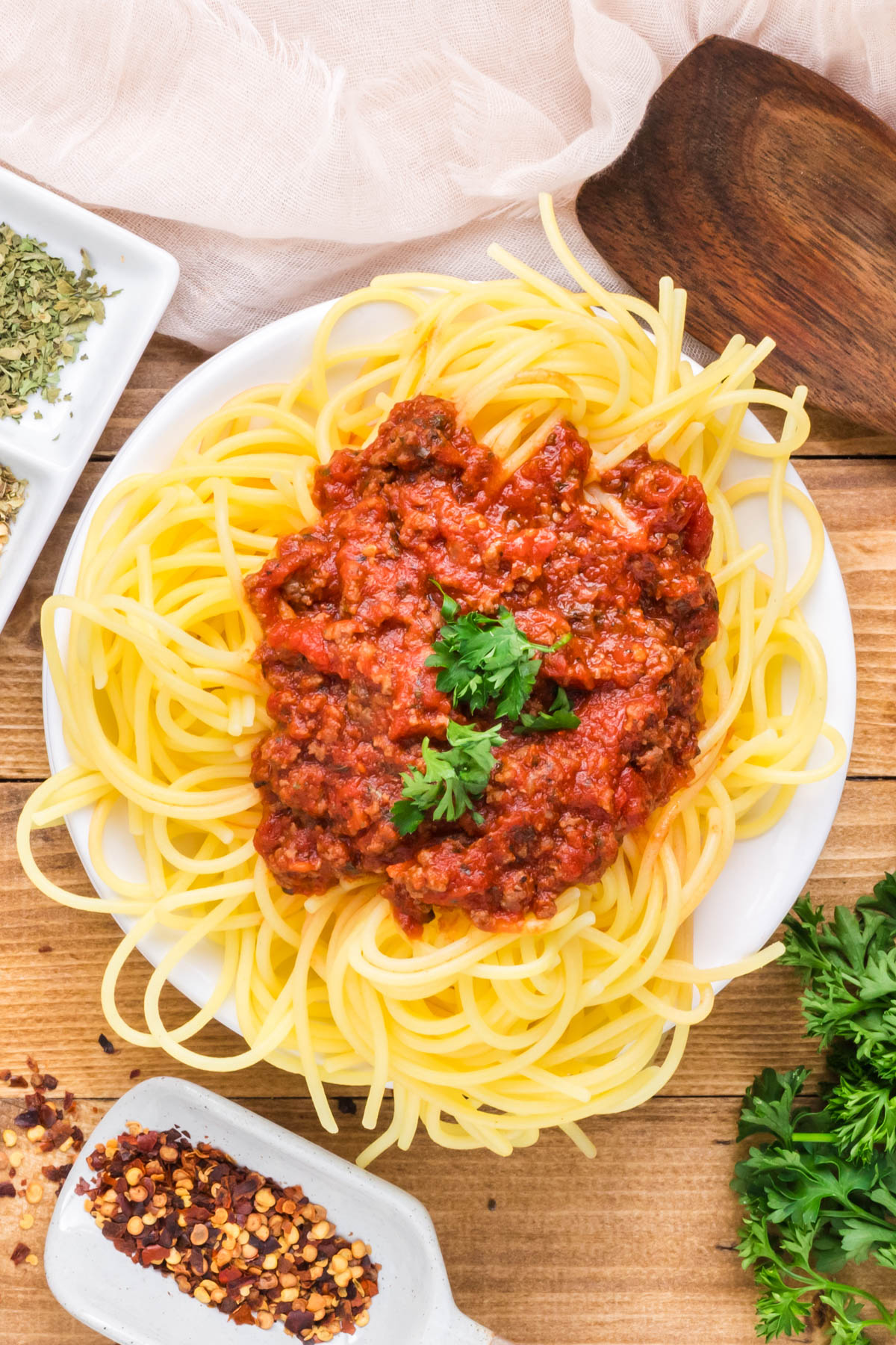 An overhead image of meat sauce on cooked spaghetti.