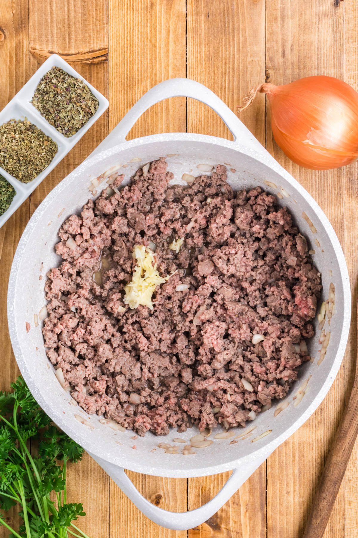 Browned ground beef with minced garlic in a pan.