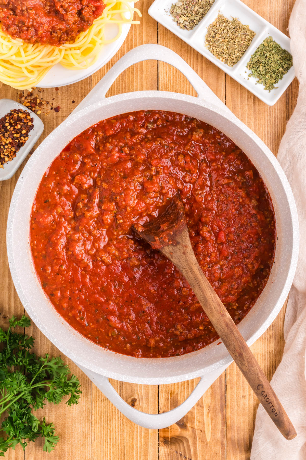 A pot of meat sauce with a wooden spoon in it.