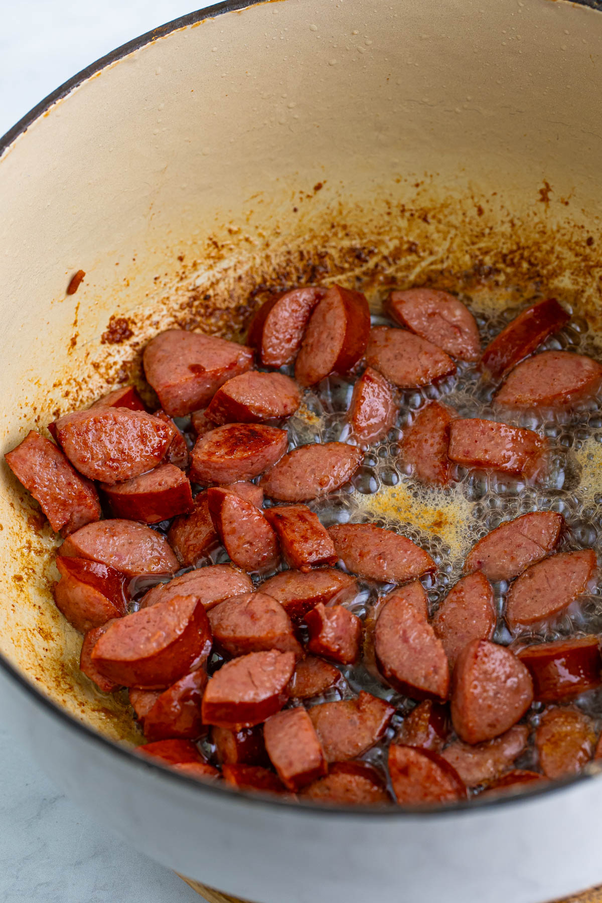 Kielbasa sausage is browning in a large pot.