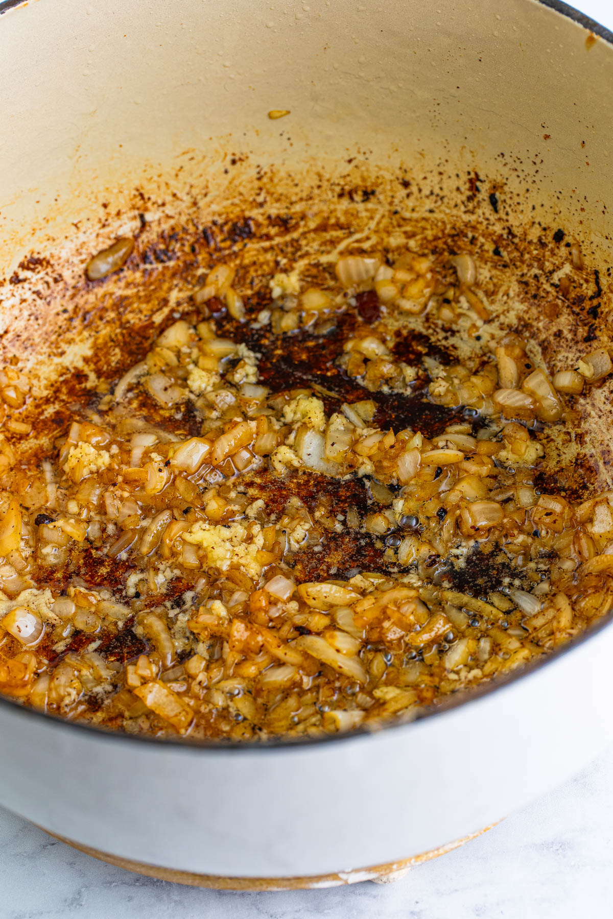 Onions and garlic are browning in a pot with bacon grease. 