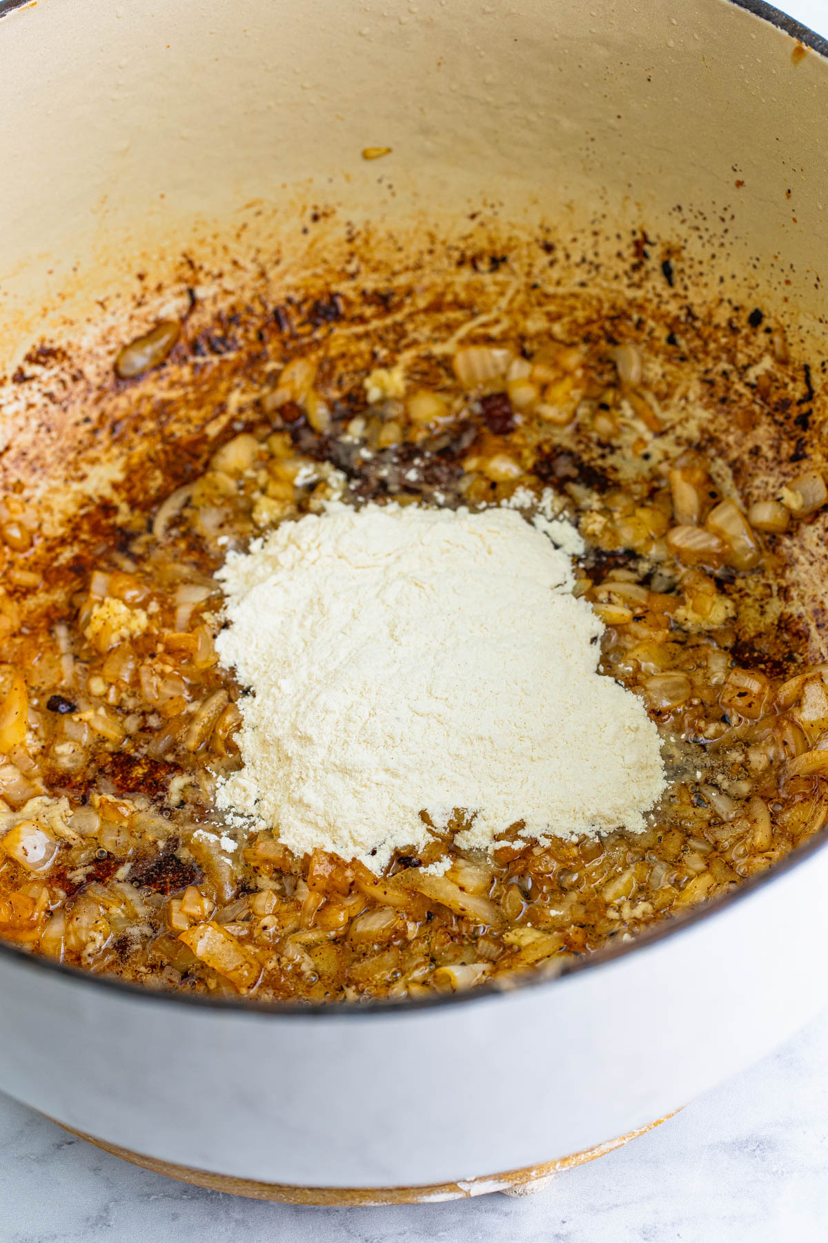 Flour is added to browned onions and garlic to thicken the base for Kielbasa corn chowder.