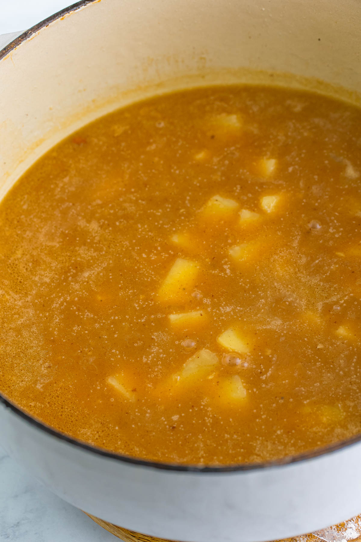 Cubed russet potatoes are added to a pot containing Kierbasa corn chowder ingredients. 