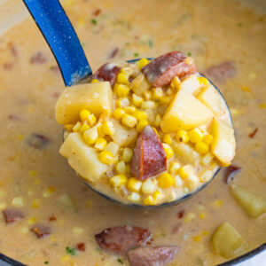 A ladle lifting a spoonful of kielbasa corn chowder.